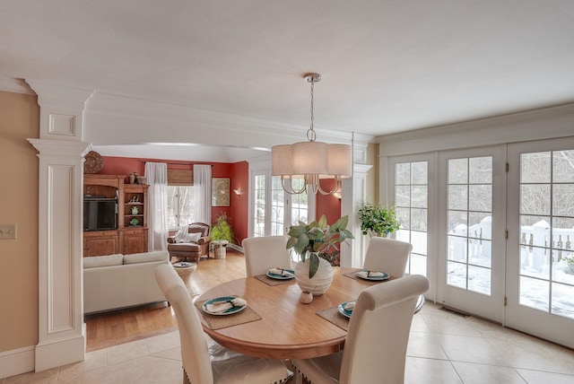 dining space featuring decorative columns, crown molding, light tile patterned floors, and a chandelier