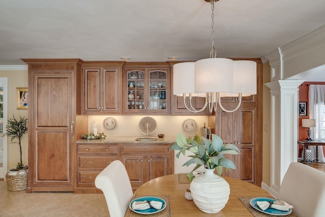 tiled dining space featuring crown molding and ornate columns