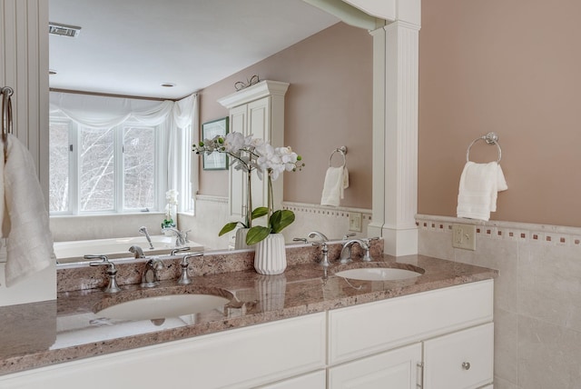 bathroom with ornate columns, vanity, and tile walls