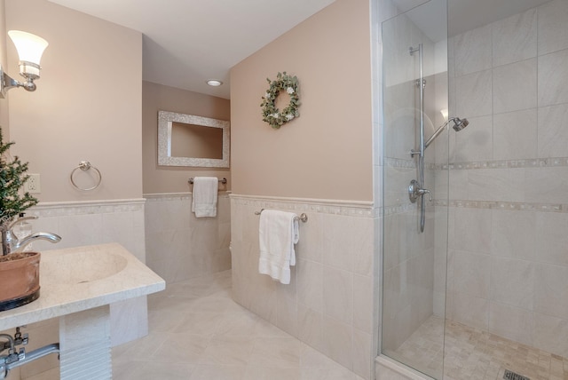 bathroom with vanity, tiled shower, tile walls, and tile patterned floors