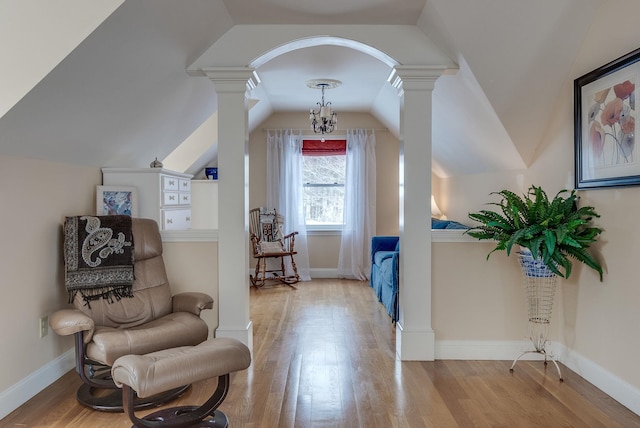 living area featuring lofted ceiling, light hardwood / wood-style floors, and ornate columns