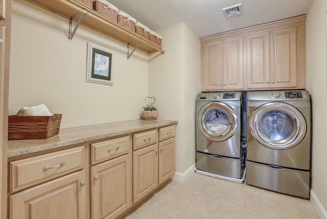 laundry area with cabinets, washing machine and dryer, and light tile patterned floors