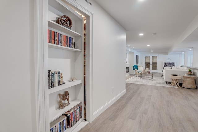 hallway featuring light wood-type flooring and built in shelves