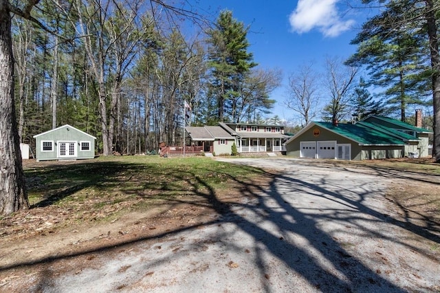 view of front of home with driveway, a porch, and an outdoor structure