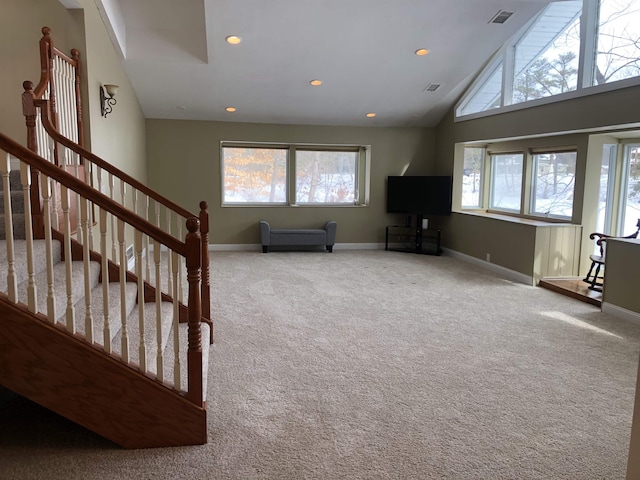 living room featuring high vaulted ceiling, plenty of natural light, visible vents, and carpet