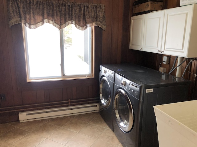 laundry room featuring a baseboard heating unit, washing machine and clothes dryer, cabinet space, and wooden walls