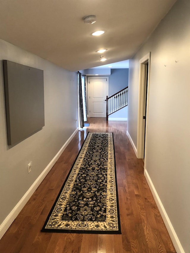 corridor with dark wood-style floors, stairs, and baseboards