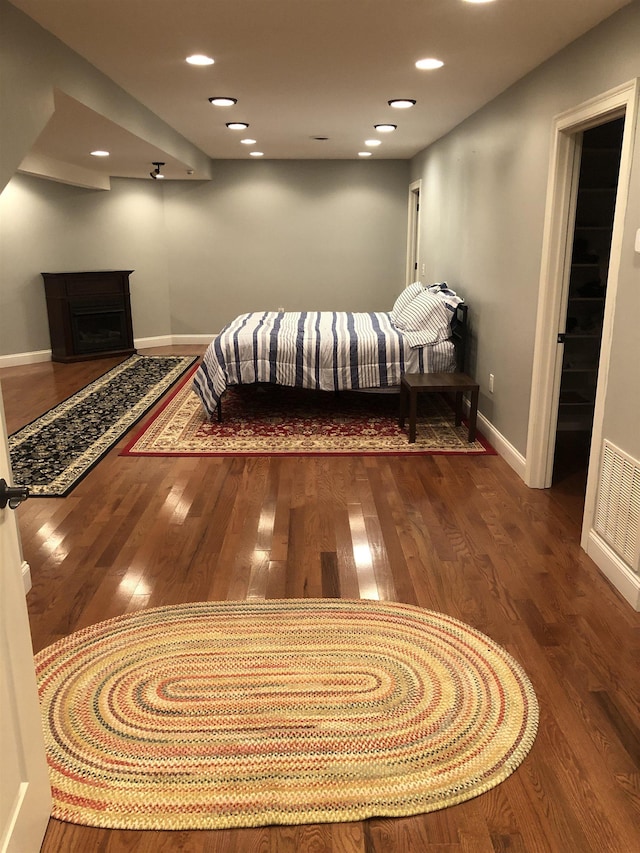 bedroom with recessed lighting, a fireplace, wood finished floors, visible vents, and baseboards