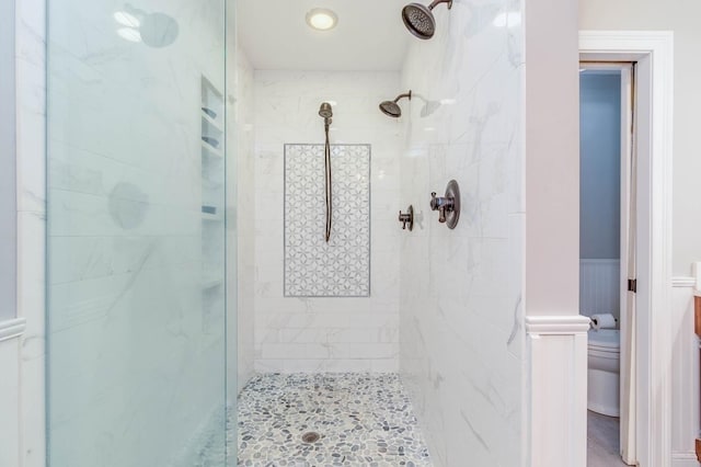 full bath with wainscoting, a shower stall, and toilet