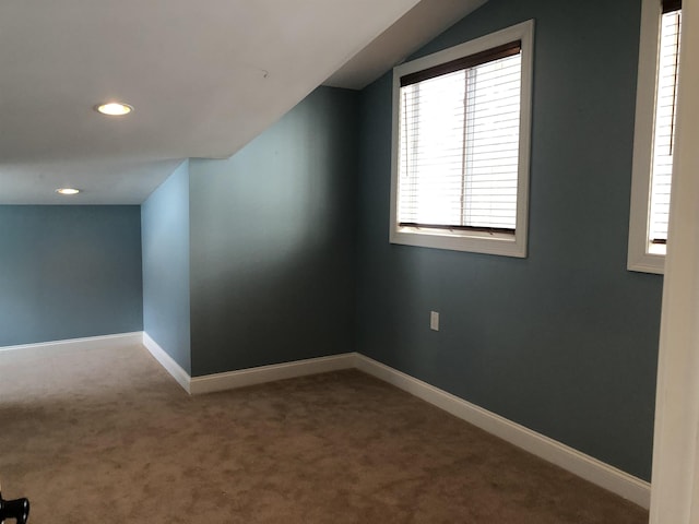 spare room featuring carpet floors, baseboards, a wealth of natural light, and lofted ceiling