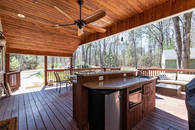 deck with outdoor dry bar, ceiling fan, and an outdoor living space