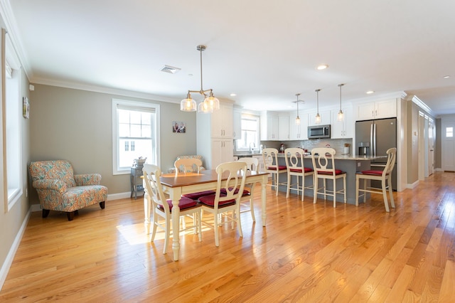 dining space featuring crown molding and light wood-type flooring