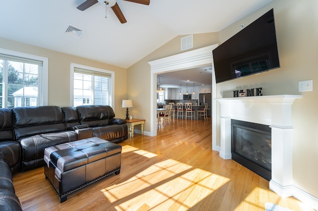 living room with lofted ceiling, hardwood / wood-style floors, and ceiling fan