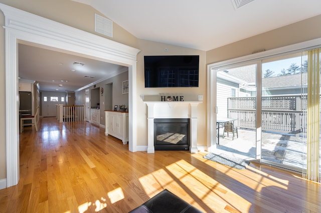 unfurnished living room with lofted ceiling, ornamental molding, and light wood-type flooring