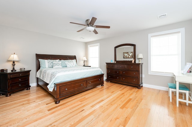 bedroom with ceiling fan, multiple windows, and light hardwood / wood-style flooring