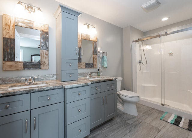 bathroom with vanity, a shower with door, and toilet