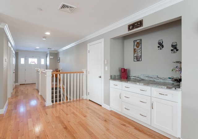 hall with ornamental molding and light wood-type flooring