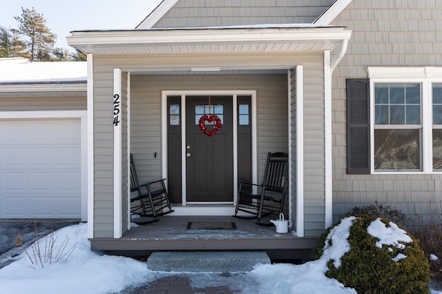 snow covered property entrance with a garage