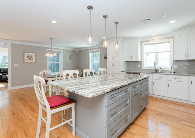 kitchen with white cabinetry, decorative light fixtures, a breakfast bar, and a kitchen island