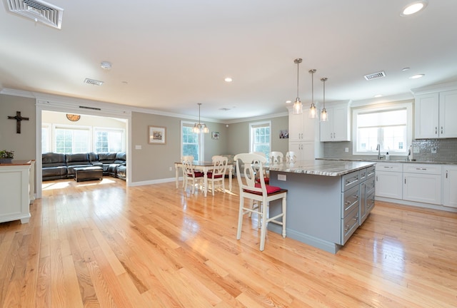 kitchen with light stone countertops, a breakfast bar, a kitchen island, and white cabinets