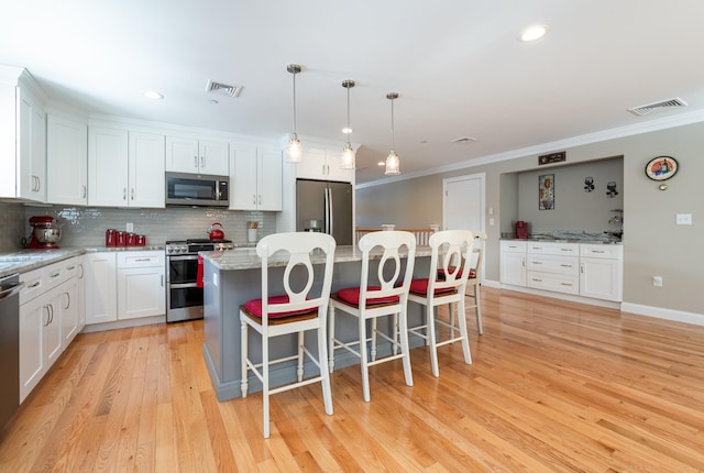 kitchen featuring pendant lighting, a breakfast bar area, appliances with stainless steel finishes, white cabinetry, and a kitchen island