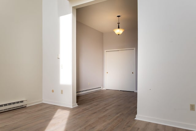 empty room featuring a baseboard heating unit and hardwood / wood-style floors