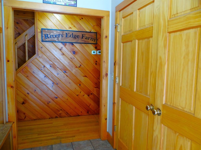 corridor featuring wooden walls and light tile patterned floors