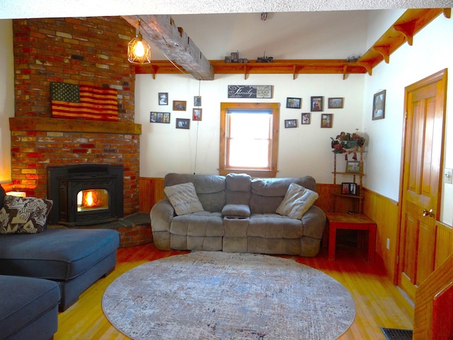 living room featuring beamed ceiling, wood walls, and light wood-type flooring