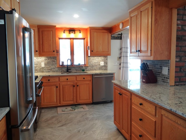 kitchen with light stone counters, stainless steel appliances, sink, and tasteful backsplash