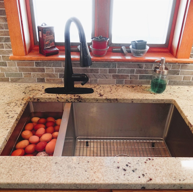 details with light stone countertops, sink, and decorative backsplash