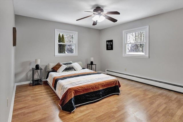 bedroom featuring multiple windows, ceiling fan, light hardwood / wood-style flooring, and a baseboard radiator