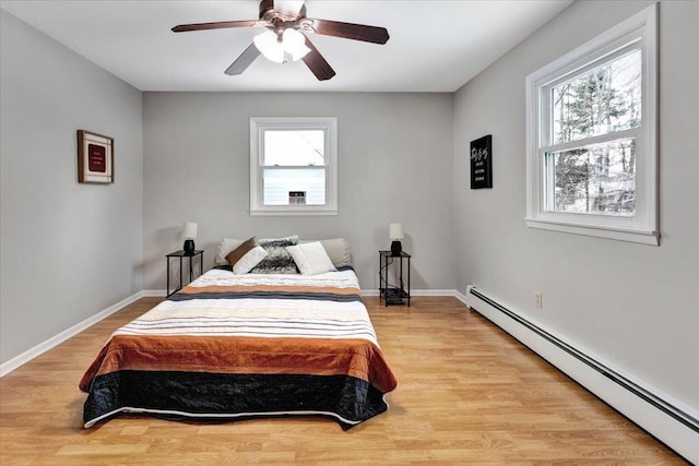 bedroom featuring multiple windows, a baseboard radiator, ceiling fan, and light hardwood / wood-style flooring