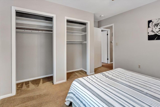 bedroom with light carpet and multiple closets