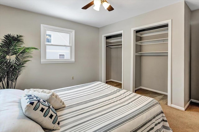 carpeted bedroom featuring multiple closets and ceiling fan