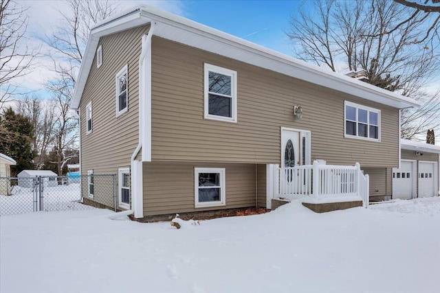 snow covered rear of property with a garage