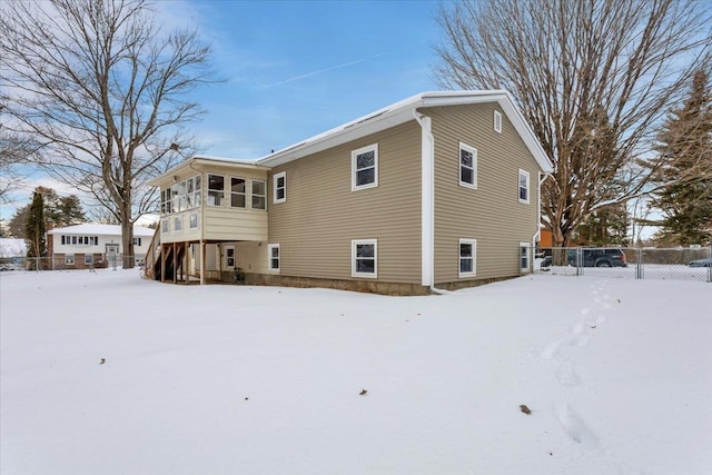 snow covered back of property with a sunroom