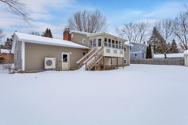 snow covered back of property featuring a sunroom and ac unit