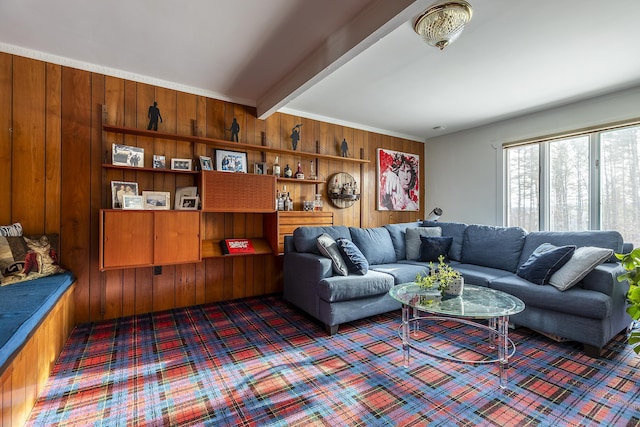 carpeted living room with beamed ceiling and wood walls