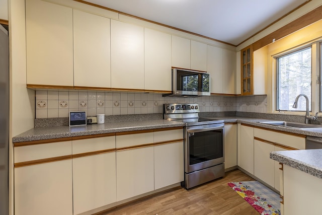 kitchen with sink, backsplash, light wood-type flooring, and appliances with stainless steel finishes