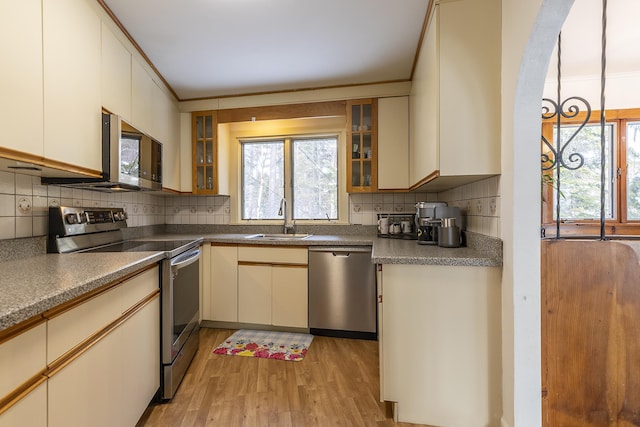 kitchen with sink, decorative backsplash, light hardwood / wood-style floors, stainless steel appliances, and cream cabinetry