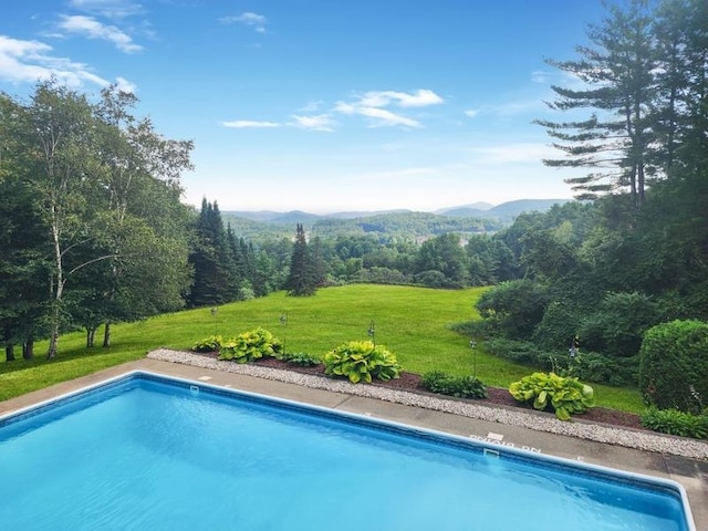 view of pool with a mountain view and a lawn