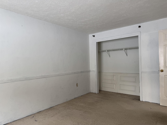 unfurnished bedroom with carpet flooring, a textured ceiling, and a closet