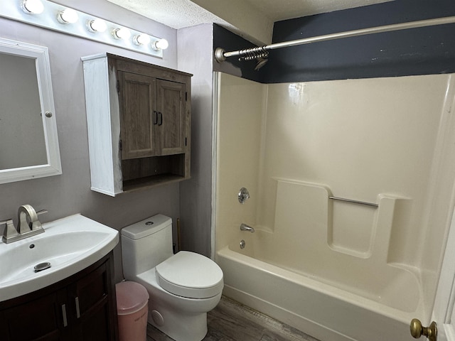 full bathroom with toilet, a textured ceiling, hardwood / wood-style floors, vanity, and tub / shower combination