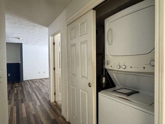 laundry area with stacked washer and clothes dryer, dark hardwood / wood-style flooring, and a textured ceiling