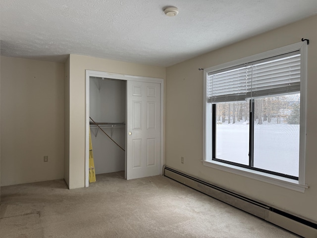 unfurnished bedroom featuring baseboard heating, a closet, a textured ceiling, and light colored carpet