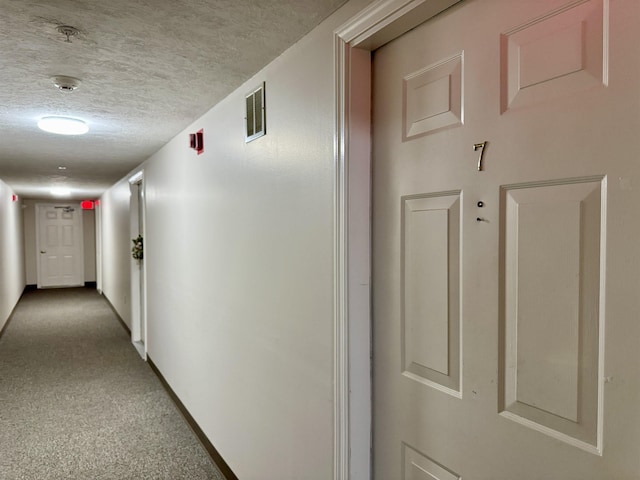 hallway with carpet and a textured ceiling