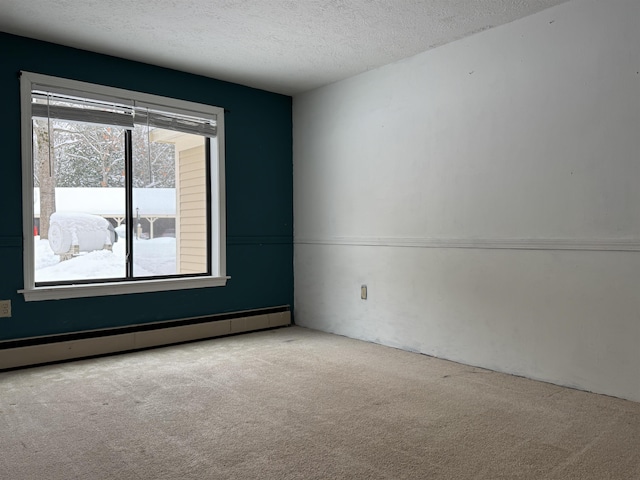 spare room featuring baseboard heating, carpet flooring, and a textured ceiling