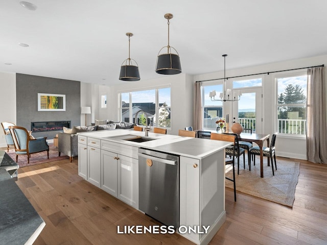 kitchen featuring white cabinetry, a kitchen island with sink, stainless steel dishwasher, and decorative light fixtures