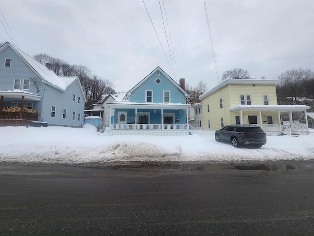 snow covered back of property with a porch