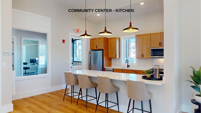 1 Longview Dr Unit 207, Atkinson, NH 03811 - kitchen featuring sink, a breakfast bar area, hanging light fixtures, stainless steel appliances, and light hardwood / wood-style flooring